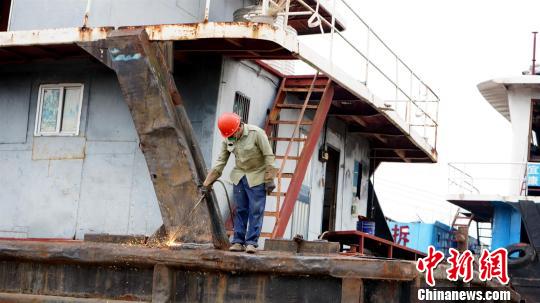 一名工人正在拆解合法采砂工程船 熊先春 摄