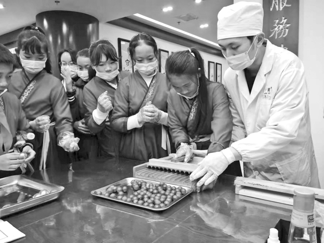 ▲小学生在体验昆中药搓大蜜丸技艺   杨祝庆 摄